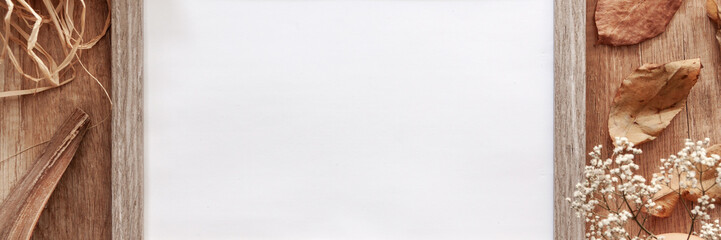 Panoramic photo of an empty mockup frame on an autumn desk with leaves, white flowers, old envelopes and dried decoration