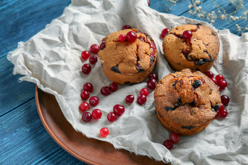 Tasty cranberry muffins on wooden table