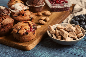 Board with tasty muffins on wooden table