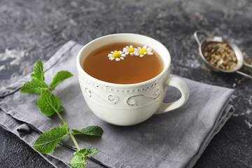 Cup of delicious camomile tea on grunge table