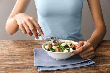 Woman eating healthy fresh salad at wooden table