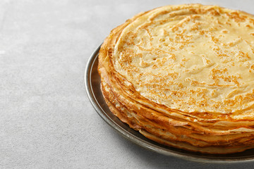 Plate with tasty thin pancakes on light table, closeup