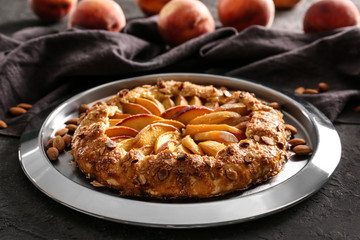 Plate with delicious peach galette on grunge table, closeup