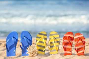Naklejka premium Set of beach flip-flops on sand near sea