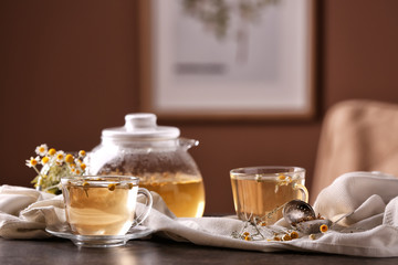 Fototapeta na wymiar Glass cups and teapot of delicious chamomile drink on table