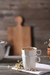 Cups of delicious chamomile tea on wooden table
