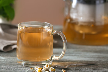 Glass cup of delicious chamomile tea on wooden table