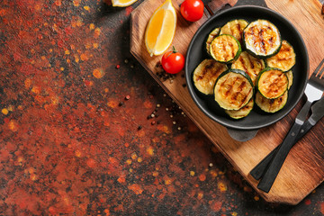 Pan with tasty grilled zucchini on color table