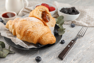 Tasty croissants with jam on plate