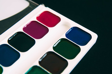 The workspace of artist for drawing. Colored pencils, watercolor, paints, brush, white paper isolated on background table.