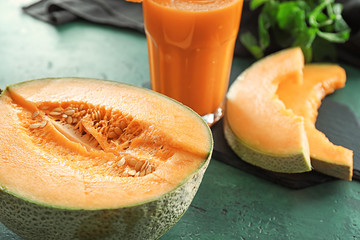 Ripe melon and glass of delicious smoothie on green table, closeup