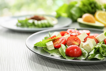 Plate with healthy fresh salad on light table, closeup