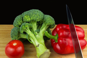 Red pepper, tomato and broccoli with stainless steel knife