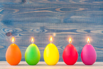 A row of colored candles on a wooden background, preparation for Easter