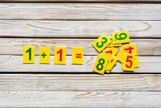 One plus one concept. Mathematics. School knowledge. Primary School. Digits on a wooden background. Doubts and thinking.