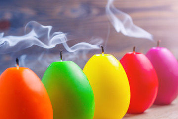 Beautiful egg candles with extinguished wick, smoke above candles