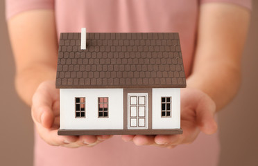 Man holding house model on color background, closeup. Mortgage concept