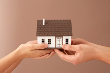Fototapeta na wymiar Man and woman holding house model on color background. Mortgage concept