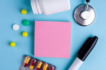 Stethoscope, tablets, medicament, capsules and stickers for notes on a blue background. Write down messages, reminders, medical prescriptions, the name of medicines, medical preparations. Copy space