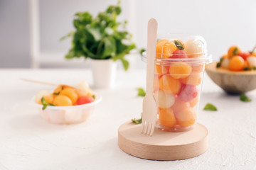 Plastic cup with tasty melon balls on table