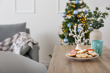 Plate with sweet Christmas cookies on table in room