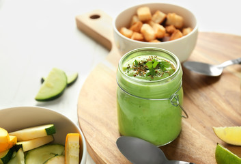 Tasty zucchini soup in jar on wooden board