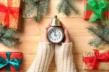 Woman with alarm clock on wooden table, top view. Christmas countdown