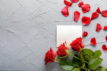 Beautiful red roses and card on grey background