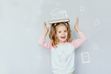 back to school. funny little girl from elementary school keeps a book on her head. education. child with book. selective focus. concept of education. the symbolism of the school.