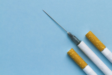 Cigarettes and needles for injections on a blue background. The concept of tobacco, cigarette, nicotine, drug addiction. Harm to health. Concept stop smoking. Top view. Copy space