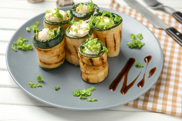 Tasty zucchini rolls with cheese on plate