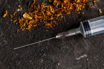 Cigarettes, needles for injections on a black background. Treatment of nicotine addiction. Danger to life. Stop smoking