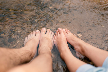 Closeup Men's feet and women's feet soaked in stream water