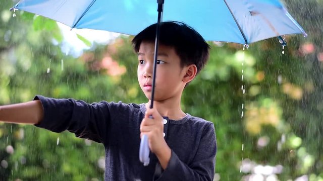 Young Asian boy stan under the rain