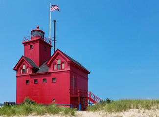 red lighthouse in Holland Michigan harbor with blue sky background © driftwood