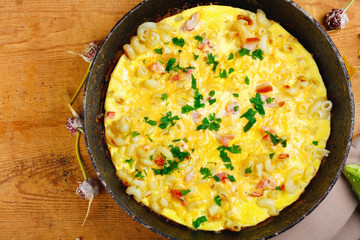 Traditional rustic omelette with bacon, pasta and greens .  Copy space