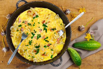 Traditional rustic omelette with bacon, pasta and greens .  Copy space