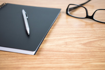 Side view of a businessman with a pen and notebook at the ready on the table. Close up