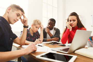 Group of diverse students studying at wooden table
