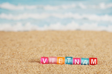Word VIETNAM from multicolored cubes in the sand on the background of beach and sea © Stanislaw Mikulski
