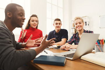 Group of diverse students studying at wooden table