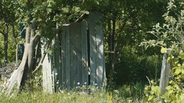 Outdoor wooden toilet located in the yard of a rural house. 4K