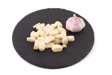 Cloves of garlic on a slate plate, isolated on white background.
