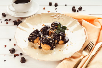 French profitroles with chocolate icing and mint leaves