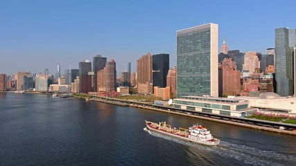 Aerial Drone Footage of New York City flying towards Manhattan skyline over a Boat at East River in Gantry Plaza State Park in Long Island City 4k