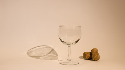 Empty glass of wine with wine stoppers (cork) inside on a white