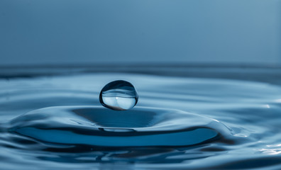 Fototapeta na wymiar single water drop splashing in a body of water