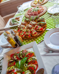 Snacks, bruschetta and salad with cheese and tomatoes with pesto sauce. The banquet table is served.
