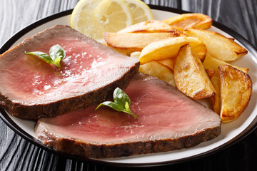 Sliced beef steak with a fried potato close-up on a plate. horizontal