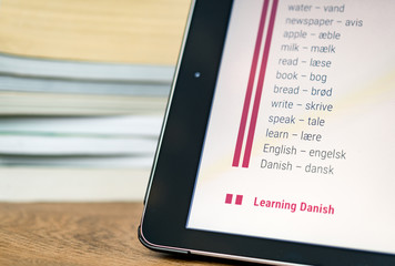 Learning Danish using a tablet with books in the background.